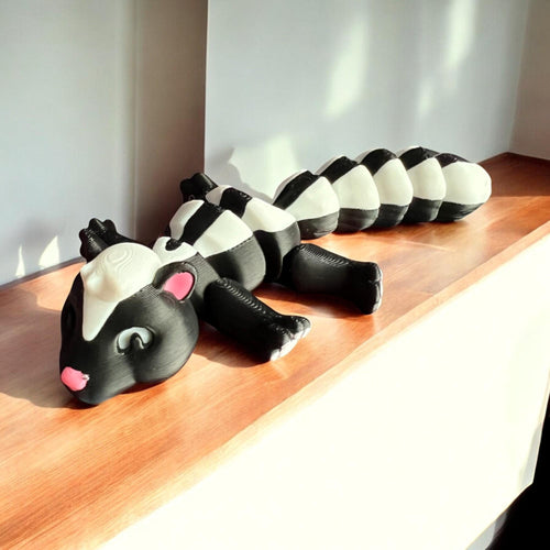 Front view of a 3D-printed black and white articulated skunk fidget toy, showcasing its cute design with a flexible segmented body